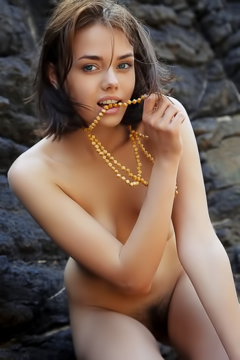 Skinny brunette takes off her dress and poses nude on rock